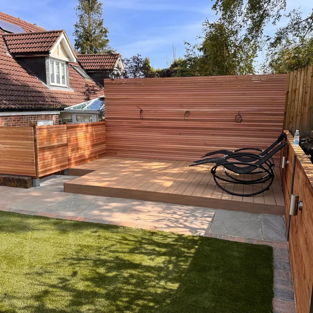 Raised cedar deck with a slatted privacy screen stepping down to an artificial lawn