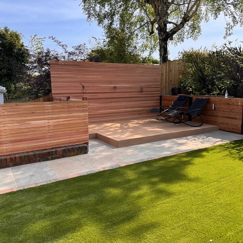 Raised cedar deck with a slatted screen beside an artificial lawn