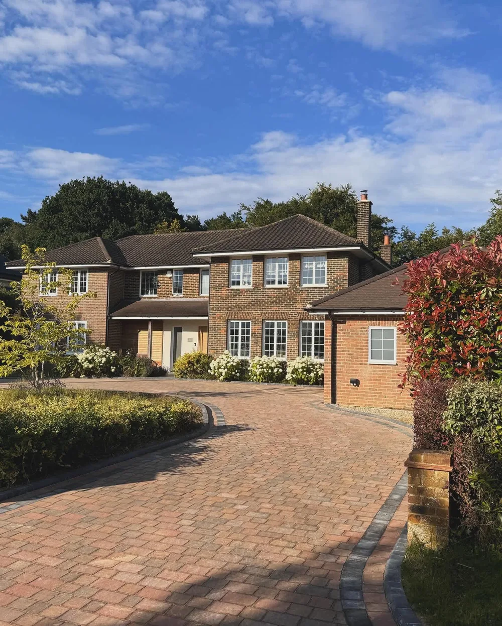 Brick paved driveway with sleeper retaining running up to a house