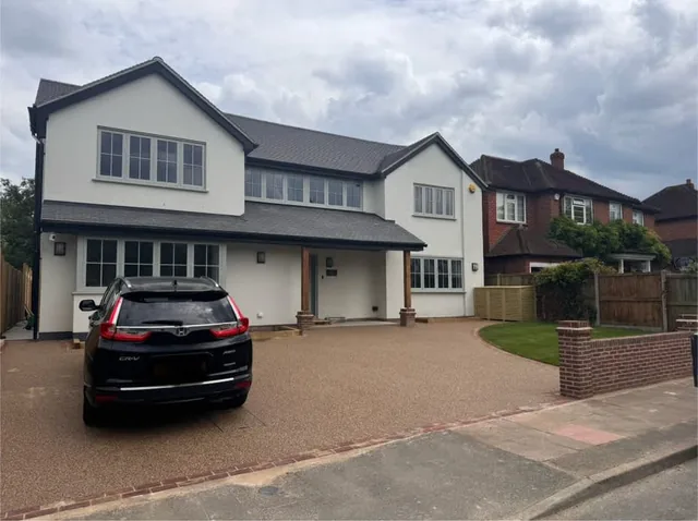 Resin-bound driveway laid to a modern white rendered house with brick edging