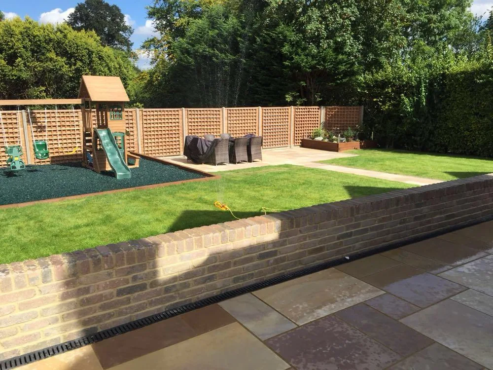 Fenced rear garden with raised sleeper beds, lawn and a paved path