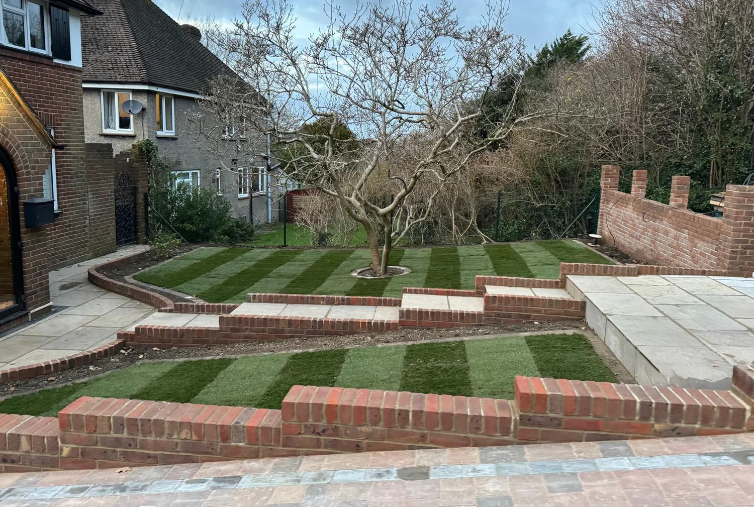 Terraced garden with new brick retaining walls, sandstone steps and striped lawns