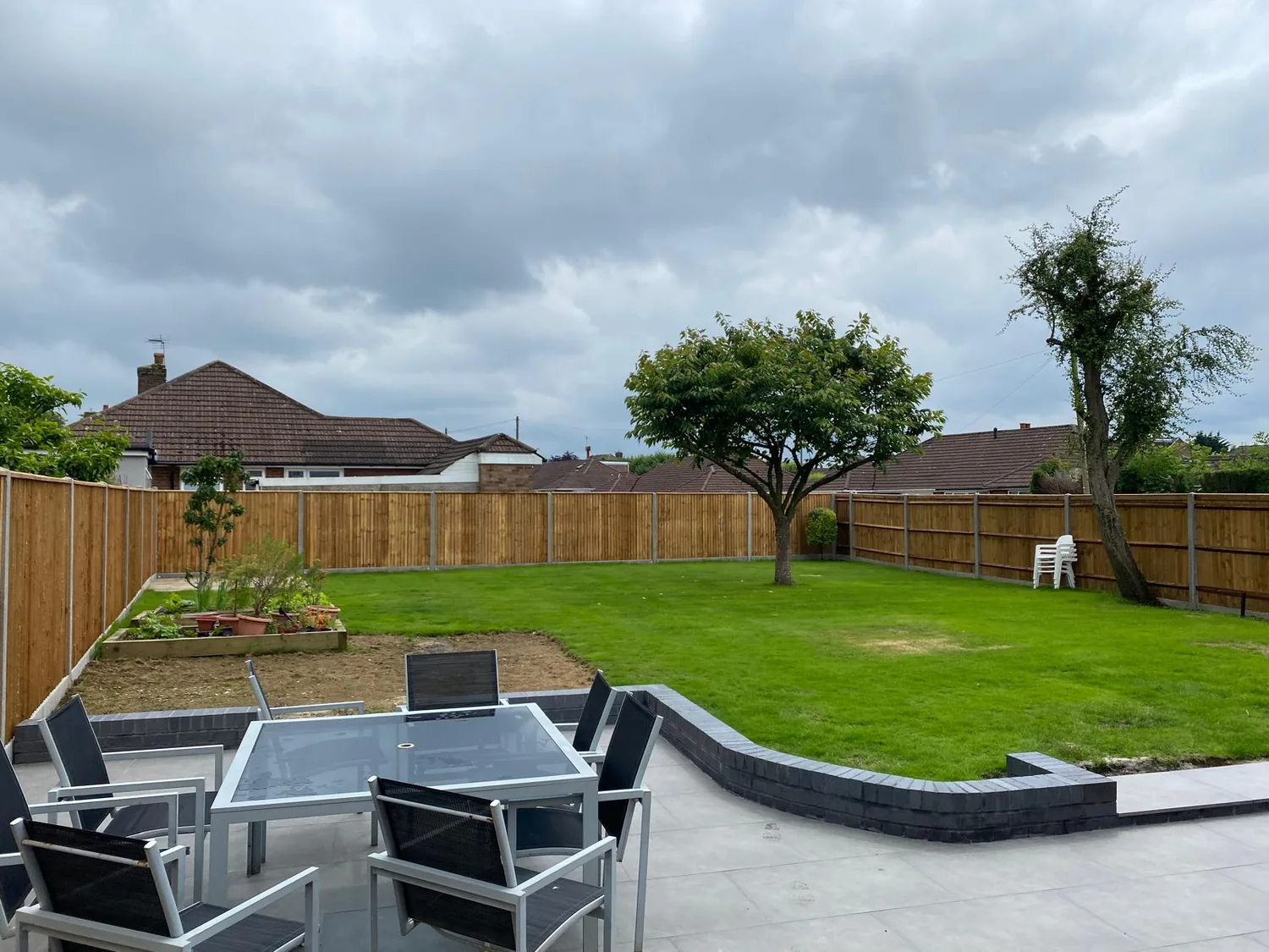 Raised lawn edged with charcoal setts above a porcelain seating terrace