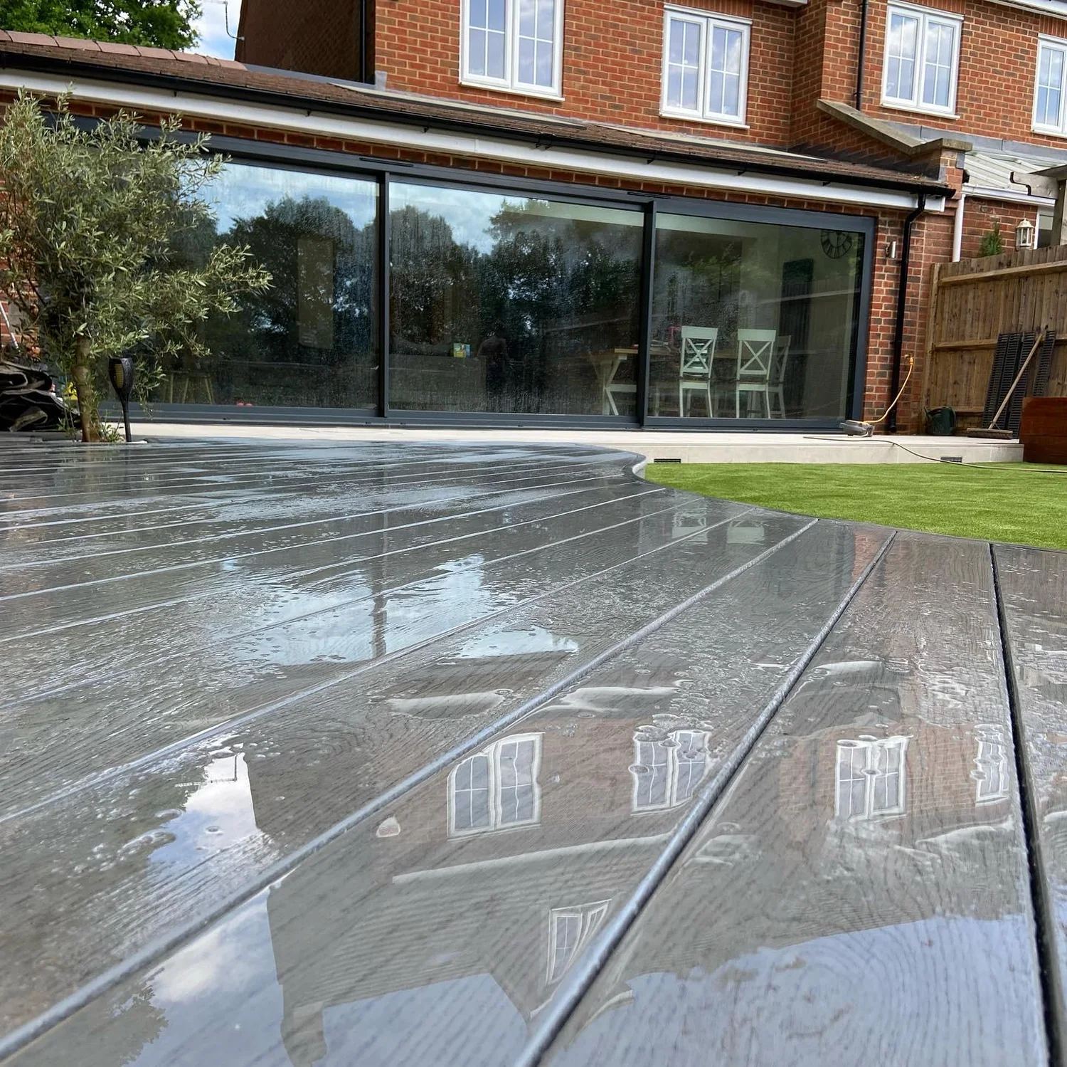 Dark porcelain terrace laid up to the sliding doors of a modern brick house