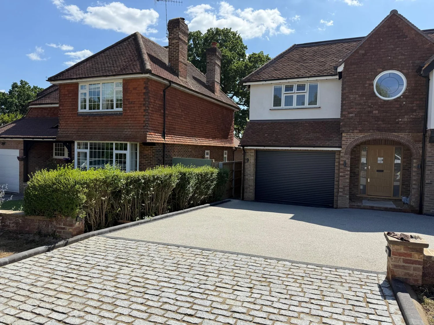 Resin-bound driveway with granite sett edging in front of a large detached house
