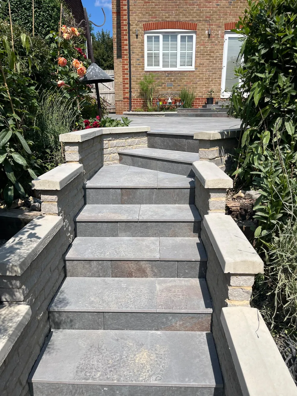 Porcelain steps with stone faced walls rising to the front door of a brick house